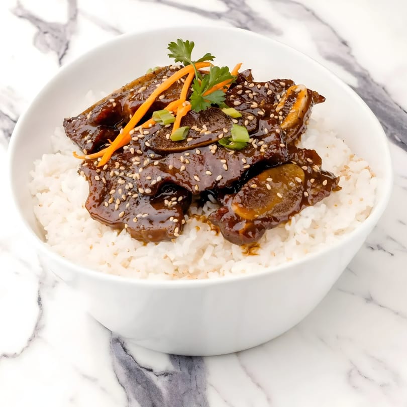 Korean BBQ short ribs (galbi) with sesame seeds, carrots, and scallions over white rice.
