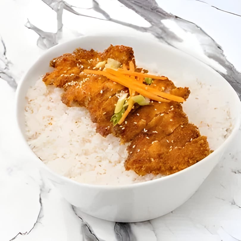Crispy Korean fried chicken cutlets over white rice, garnished with carrots and green onions.