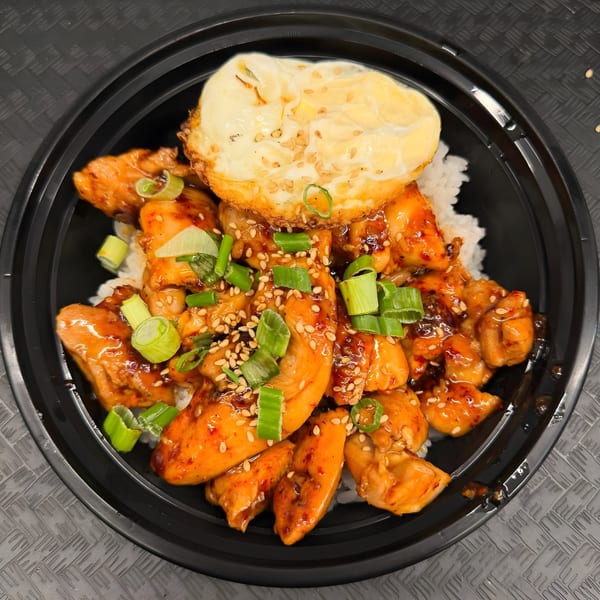Arkanseoul's Korean chicken bowl with rice, topped with a fried egg, green onions, and sesame seeds.