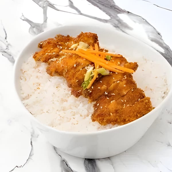 Arkanseoul's crispy Korean fried chicken cutlet, topped with carrots and green onions, served over white rice.