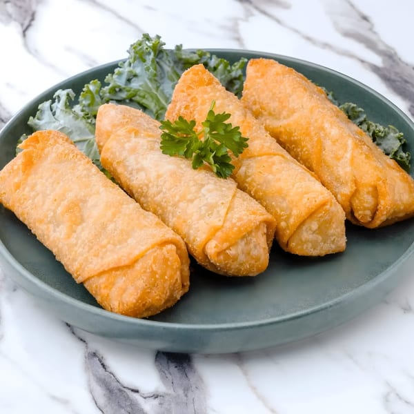 Four golden-brown Arkanseoul egg rolls with a sprig of parsley on a dark green plate.