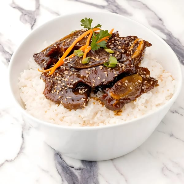Arkanseoul's Korean BBQ short ribs with sesame seeds, carrots, and scallions over white rice.