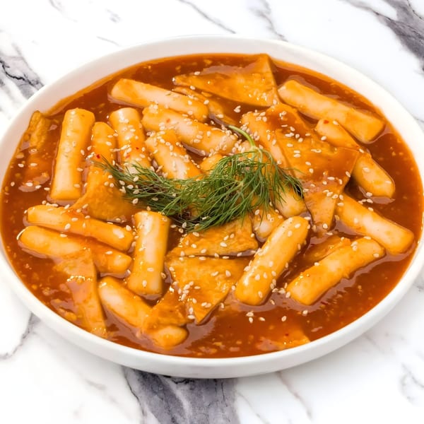Arkanseoul's Tteokbokki, a Korean dish with rice cakes and fish cakes in a spicy red sauce.